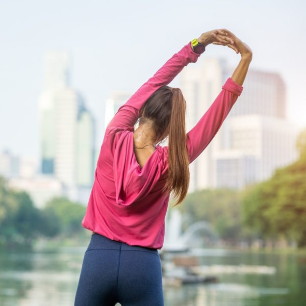 Young fitness woman runner stretching legs before run in the park