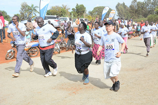  ome of the articipants in the 5km run in action alongside apan eputy ead of ission orri izumoto right during the eamganda okyo 2020 run at the oma round in apchorwa