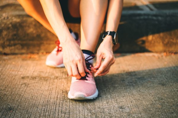 Low Section Of Woman Tying Shoelace On Street During Sunset