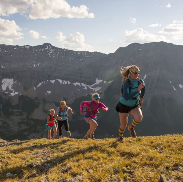 Trail runners in mid air stride towards mtn summit