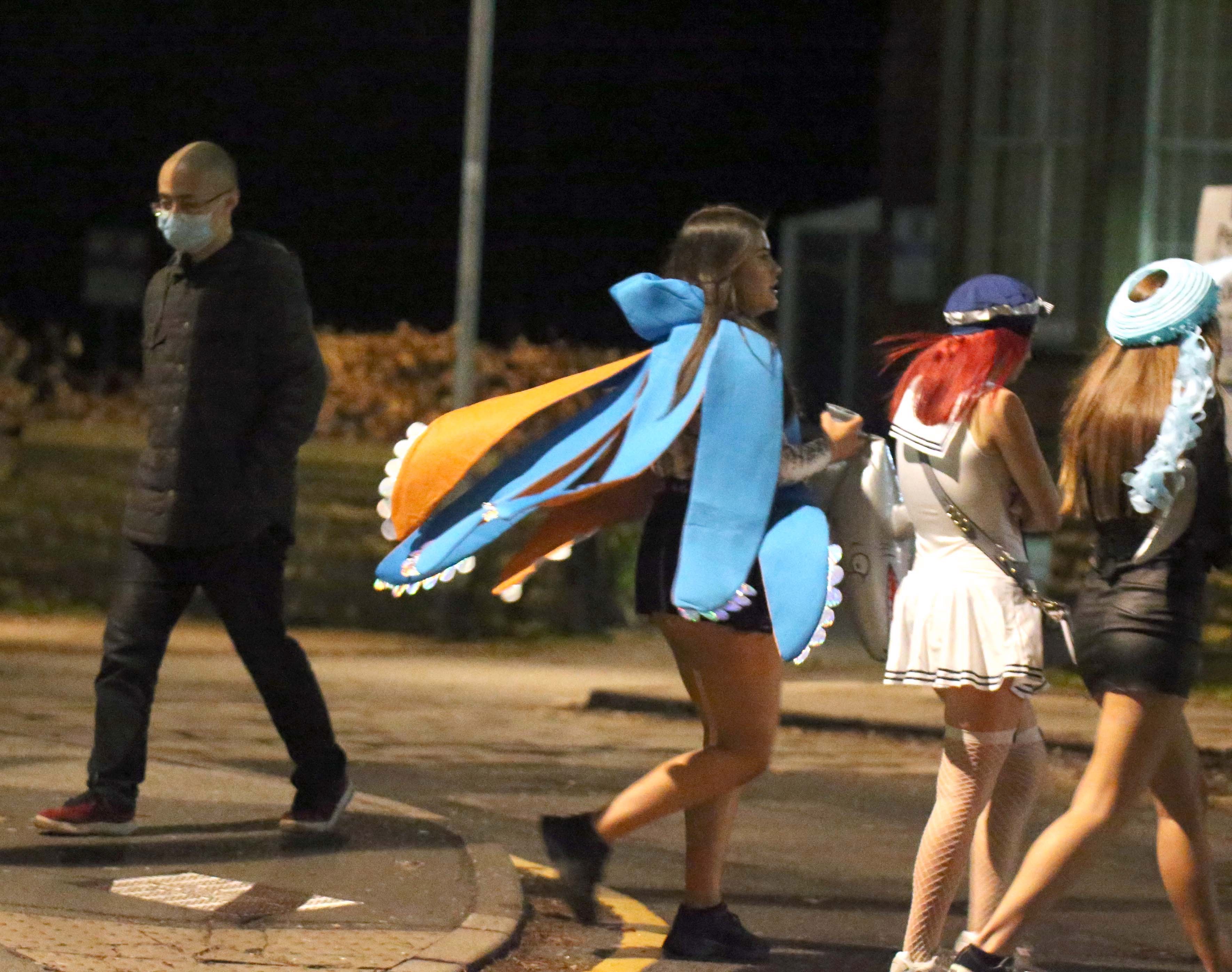  A man walking past drinkers in Leeds wearing a mask amid concerns over the virus and social gatherings