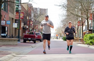 A man and woman run through downtown Kalamazoo.