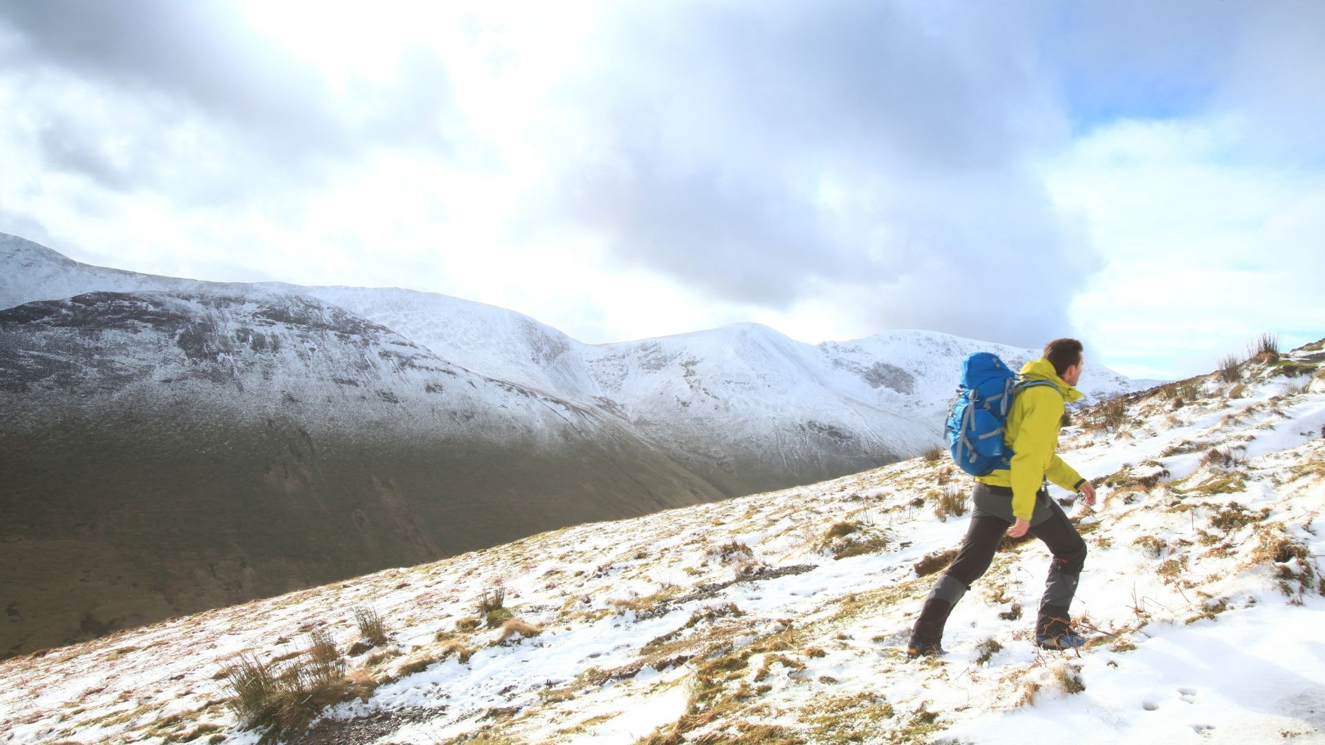 Hiker in a yellow jacket heading up Grisedale Pike in winter