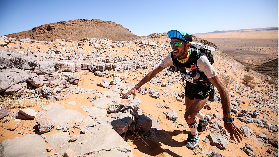 man scrambles over rocks in ultra marathon