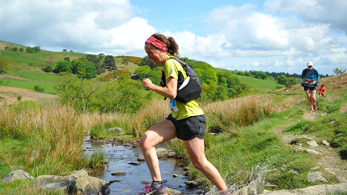woman runs across a river in a race