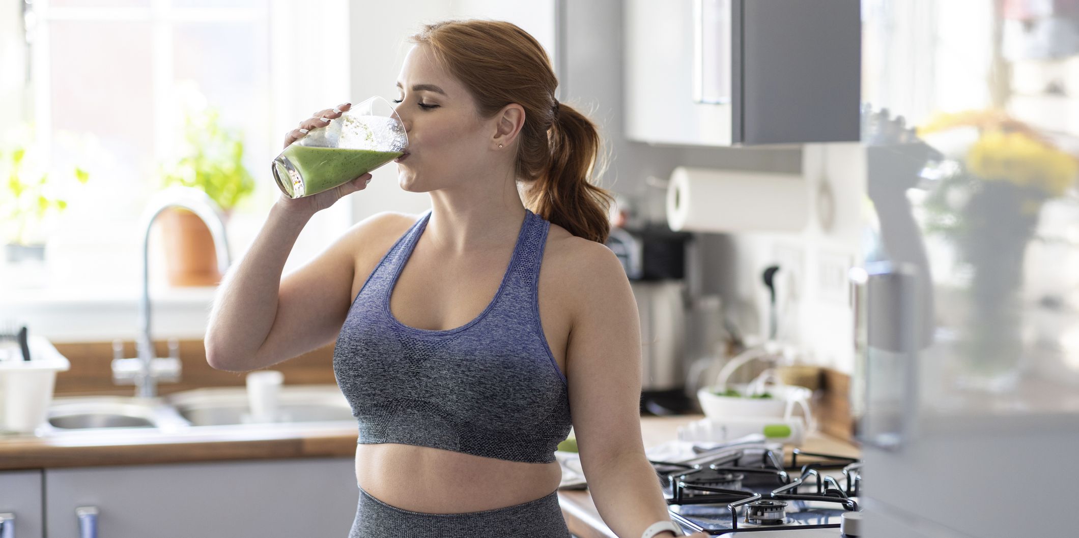 redhead woman drinking healthy milkshake after working out at home