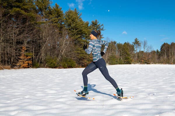 Ms. Canney jogs across a field of pristine snow with blue sky behind her. 