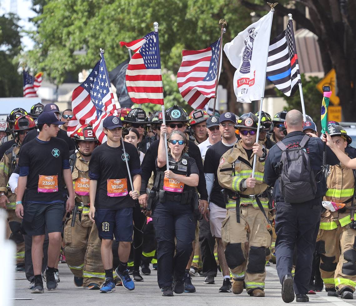 First responders including fire fighters walk together towards the finish line carrying American Flags to raise awareness about PTSD at the 18th annual Life Time Miami Marathon and Half Marathon where runners took off in the dark at 6 a.m. Sunday, February 9, 2020 in front of AmericanAirlines Arena and finished on Biscayne Boulevard near Bayfront Park. There were more than 20,000 combined runners registered for the marathon and half marathon and the second marriage proposal during the marathon.
